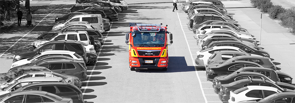 hinausautokeskuksen hinausauto ja henkilöautoja parkkipaikalla